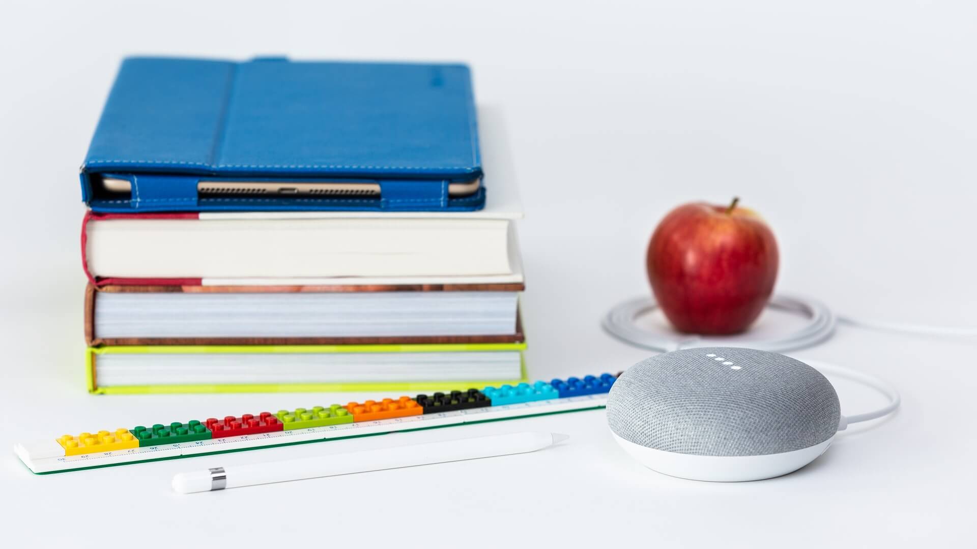 a photo of books, an apple, and speaker